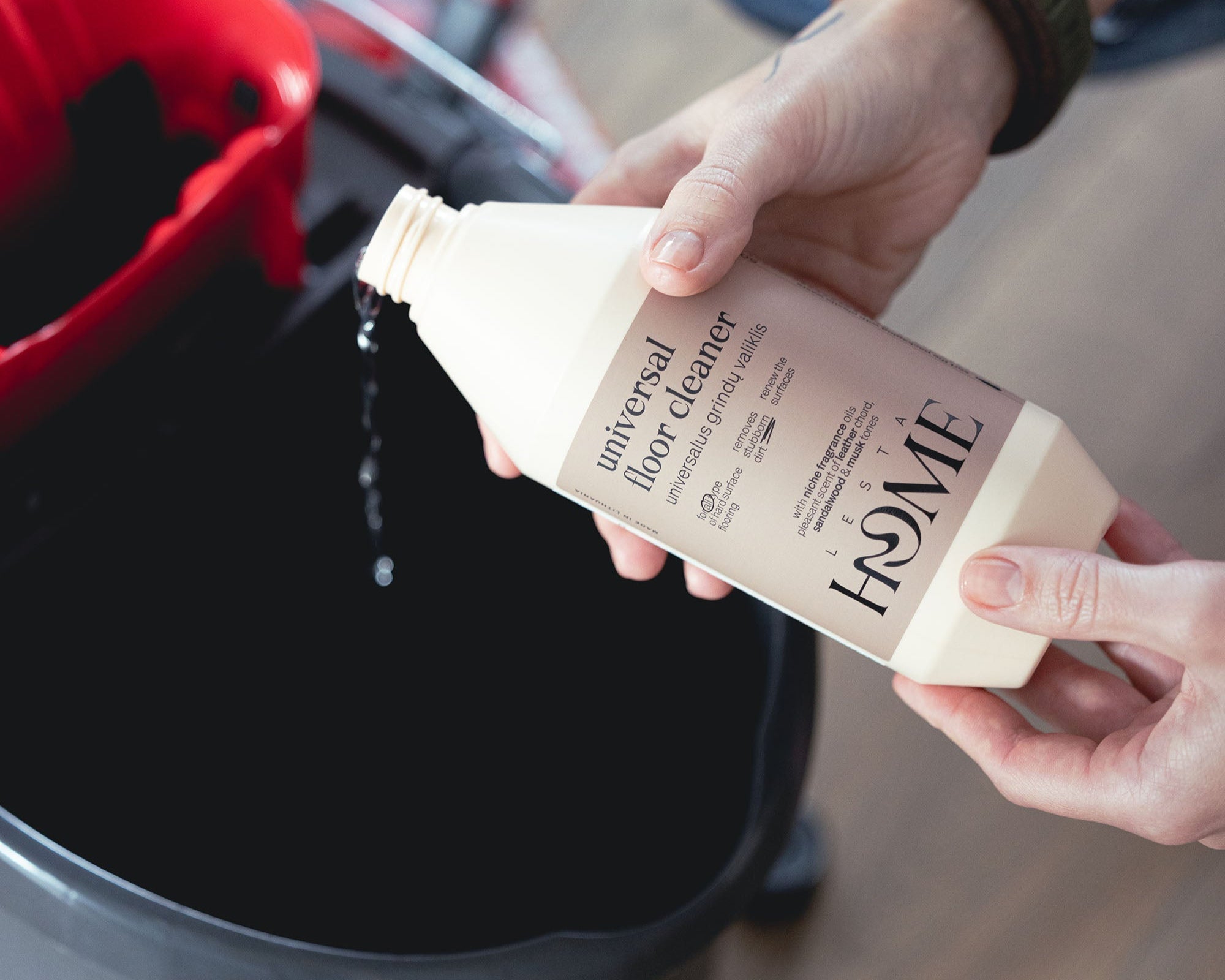 Person holding a bottle of floor cleaner over a trash can