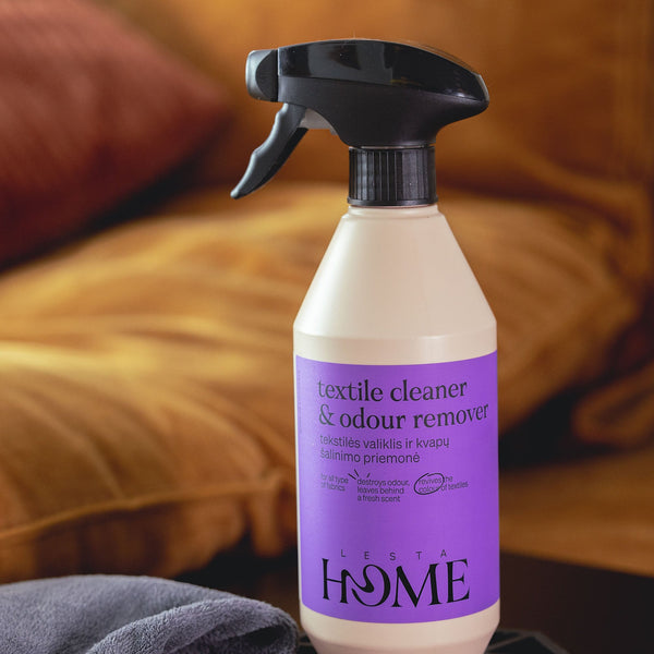 Textile cleaner and odor remover spray bottle with purple label on a blurred background