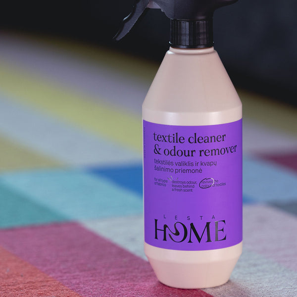 Textile cleaner & odour remover bottle with purple label on a colorful geometric patterned surface