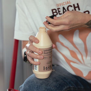 Person holding a bottle of floor cleaner with a blurred background